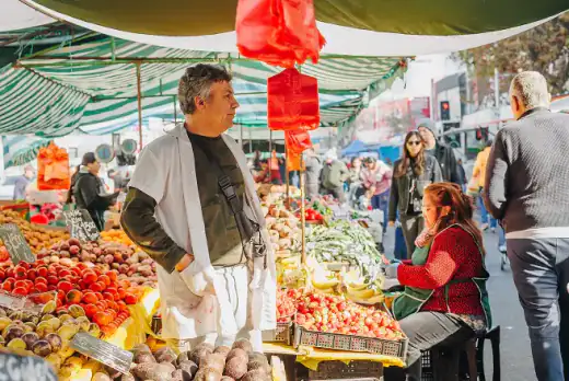 Feriante y clientes en un puesto de frutas de una feria libre