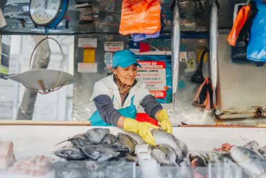 Pescadera atendiendo su puesto de pescados frescos en la feria